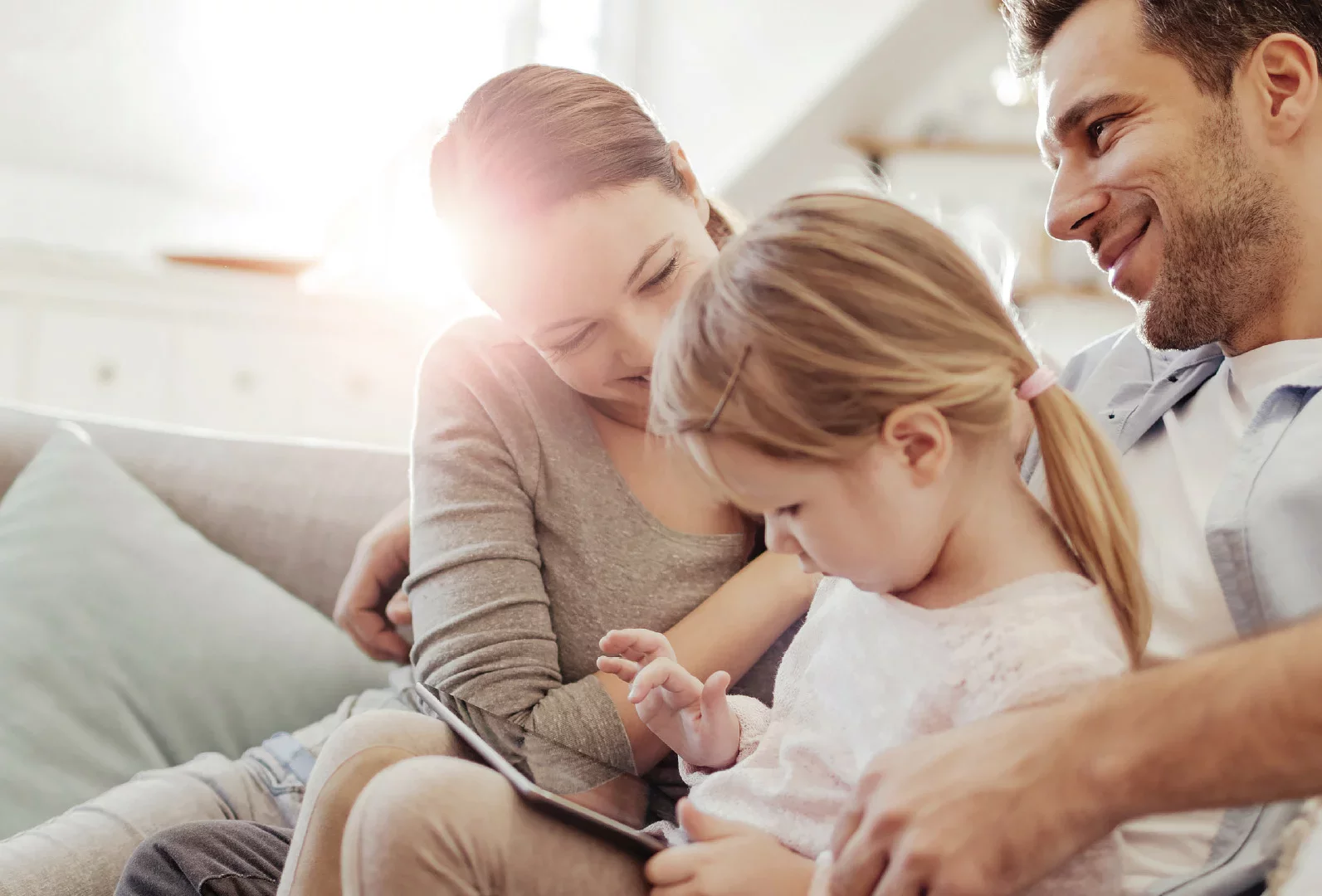 Une famille se détend dans le salon pendant que leurs enfants jouent par terre, profitant du temps ensemble.
